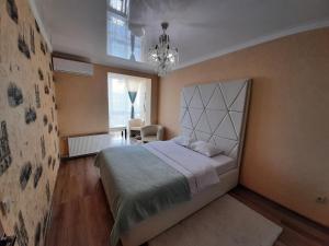 ein Schlafzimmer mit einem großen Bett und einem Kronleuchter in der Unterkunft VIP APARTMENTs in Luzk