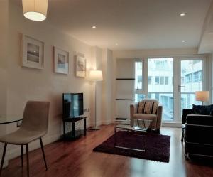 een woonkamer met een bank en een tv bij Barbican Serviced Apartments in Londen