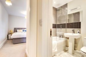 a bathroom with a sink and a toilet and a bed at Sapphire Serviced Apartment in Chelmsford