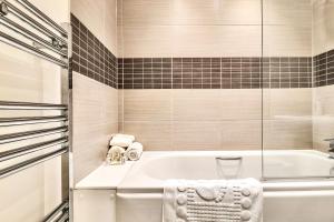 ein weißes Bad mit einer Badewanne und einer Dusche in der Unterkunft Sapphire Serviced Apartment in Chelmsford