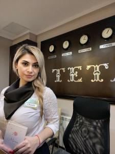 a pregnant woman standing in a room with clocks on the wall at Hotel Teta in Timashevsk