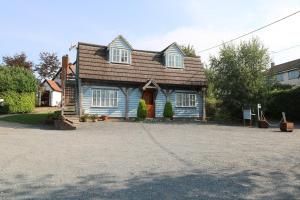 uma casa azul com um telhado castanho e uma entrada em Flink's Barn em Great Dunmow