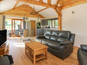 a living room with a leather couch and a table at Ploony Hill Cabin in Knighton