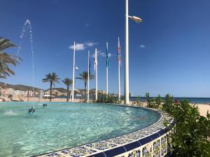 - une piscine à côté d'une plage arborant des drapeaux dans l'établissement Apartamento Mar y Montaña, à Cullera