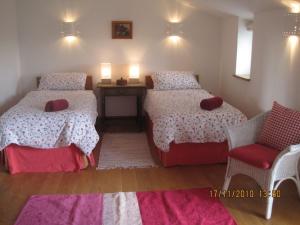 a small bedroom with two beds and a chair at Daisy Moo in Llanrhyddlad