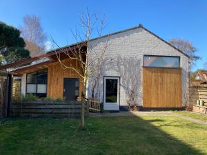 una casa con un albero di fronte di Luxe vakantiehuis met sauna De Barn Bergen a Bergen