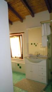 baño con lavabo, espejo y ventana en Il Portico Guesthouse en Muravera