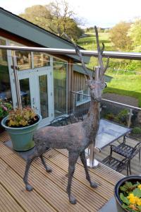 a statue of a deer standing on a deck at Black Burn Lodge B & B in Newcastleton