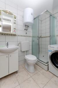 ein Badezimmer mit einem WC, einem Waschbecken und einer Waschmaschine in der Unterkunft Apartments Mila II in Tribunj