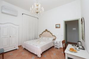 um quarto branco com uma cama e um lustre em La Cascata em Amalfi
