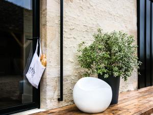 un vase blanc assis sur une terrasse couverte avec une plante dans l'établissement Chez Laurence du Tilly - L'annexe, à Colomby-sur-Thaon