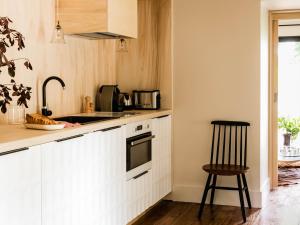 - une cuisine avec des placards blancs, un évier et un tabouret dans l'établissement Chez Laurence du Tilly - L'annexe, à Colomby-sur-Thaon