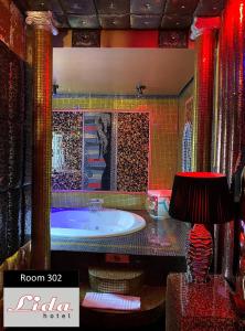 a bathroom with a tub and a table with a lamp at Lida Hotel in Athens