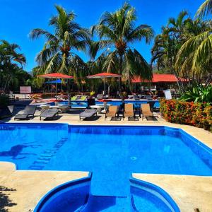 a pool at a resort with palm trees and chairs at Hotel El Regalo in Nicoya