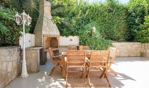 a wooden table and chairs with a grill and a table and chairs at Holiday House close to Port Aventura in Salou
