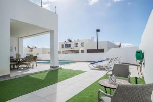 Un patio con sillas y una mesa y una piscina. en Casa Dubh Linn, en Playa Blanca