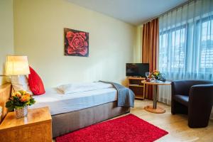 Habitación de hotel con cama, sofá y TV en Hotel Bischoff en Baden-Baden