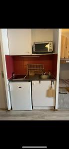 a small kitchen with white cabinets and a microwave at Charmant T2 montagne en étage élevé. in Val Thorens