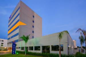 um edifício com palmeiras em frente em Transamerica Fit Rondonopolis em Rondonópolis