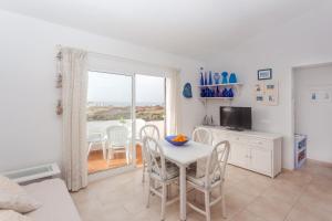uma sala de estar com uma mesa e cadeiras e uma janela em El Faro 8 em Cala'n Bosch