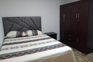a bedroom with a large bed and a black cabinet at Piso 3-Apartment near to Cali airport in Palmira