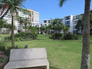 a bench in a park with palm trees and buildings at 413 BREAKERS RESORT UMHLANGA in Durban