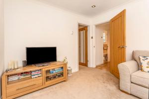 a living room with a television and a couch at Ardenlea in Bourton on the Water