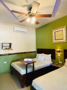 a bedroom with two beds and a ceiling fan at Hotel El Regalo in Nicoya