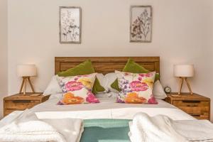 um quarto com uma cama com almofadas verdes e cor-de-rosa em Ardenlea em Bourton on the Water