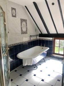 諾里奇的住宿－Wensum House，浴室铺有蓝色瓷砖,配有白色浴缸。