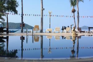 a pool of water with chairs and palm trees at Grand Sea Beach Resort in Haad Pleayleam
