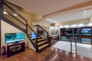 a living room with a staircase and a tv at Akroyali Hotel & Villas in Agios Andreas