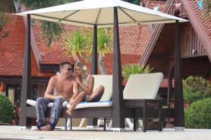 a man and a woman sitting on a chair under an umbrella at Grand Sea Beach Resort in Haad Pleayleam