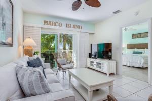 a living room with a couch and a tv and a bed at Sunshine on My Shoulders in Marco Island