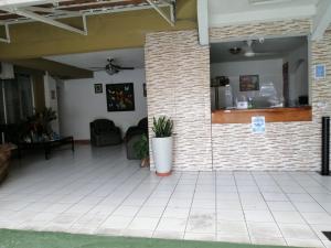a living room with a white tile floor and a brick wall at Hotel Malinche in Quepos
