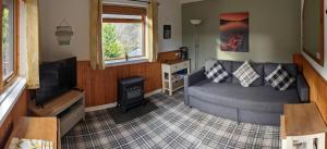 a living room with a couch and a television at An Carraig Log Cabin in Strathyre