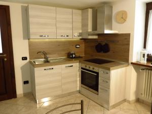 a kitchen with white cabinets and a sink and a stove at Lo Gnomo sotto al Glicine in Châtillon