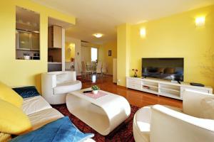 a living room with white furniture and a flat screen tv at Apartment Bella Art in Belgrade