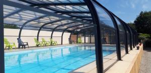 a swimming pool with a pergola next to a swimming pool at L'olivier in Tréffiagat