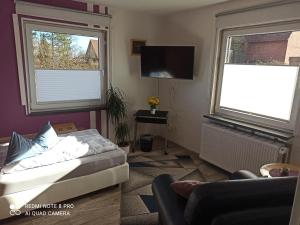 a bedroom with a bed and a tv and two windows at Ferienwohnung "An der Geest 1" in Buxtehude