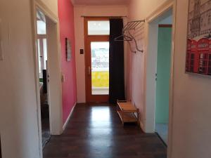 un couloir aux murs roses et une porte avec fenêtre dans l'établissement Haus Bergeshöh, à Braunlage