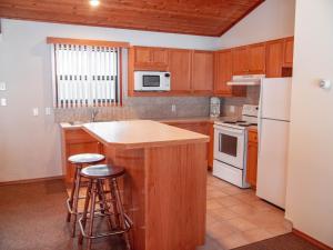 una cocina con armarios de madera y electrodomésticos blancos en Fairmont Hot Springs Resort, en Fairmont Hot Springs