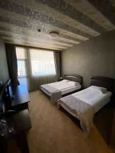 a hotel room with two beds and a desk at Hotel Aqualand in Plovdiv