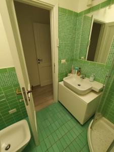 a green tiled bathroom with a sink and a toilet at Villetta Reparata in Santa Teresa Gallura