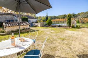 stół i krzesła z parasolem na dziedzińcu w obiekcie Villa de 2 chambres avec piscine privee jardin amenage et wifi a Sigoules w mieście Sigoulès