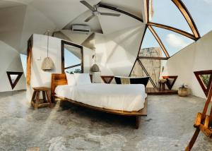 a bedroom with a large bed and large windows at Mamasan Treehouses & Cabins in Tulum