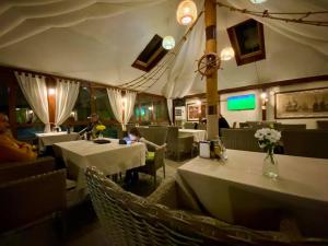 a restaurant with white tables and chairs and a child sitting at a table at Marco Polo, Cahul in Cahul