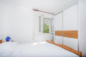 um quarto branco com uma cama e uma janela em Apartments IVOMAR em Trogir