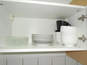 un estante blanco con platos y tazones. en Ferienwohnung Monteurzimmer Haus Arnstadt, en Arnstadt