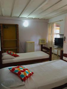 a bedroom with two beds and a television in it at Nova Aldeia Buzios in Búzios